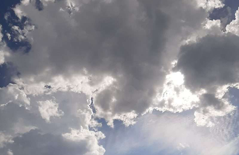 Himmel mit hellen und dunklen Wolken, dazwischen Sonne